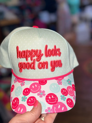 Light green hat with red 'Happy Looks Good on You' embroidery and a pink/red smiley floral print brim.