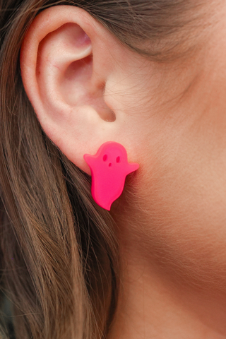 Neon pink acrylic ghost earring with a dangle design worn by a person.