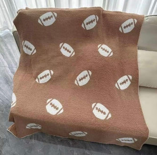 Brown blanket with white football pattern, draped over a couch.