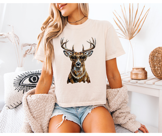 Woman wearing an ivory tee with a graphic of a deer, styled with denim shorts and a cardigan.