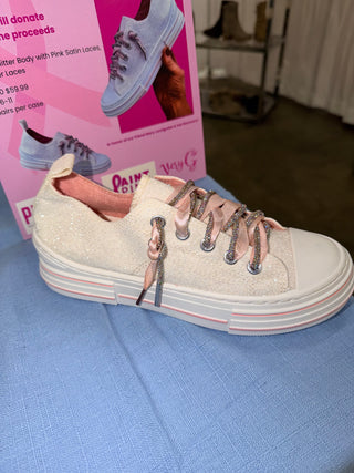 A glittery sneaker with pink satin laces and a white sole featuring pink accents.