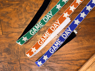 Beaded purse strap in orange and white with 'GAME DAY' text and star patterns.