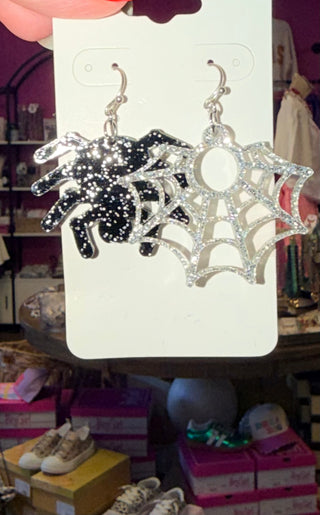 Pair of acrylic earrings featuring a black glitter spider and a silver glitter web.