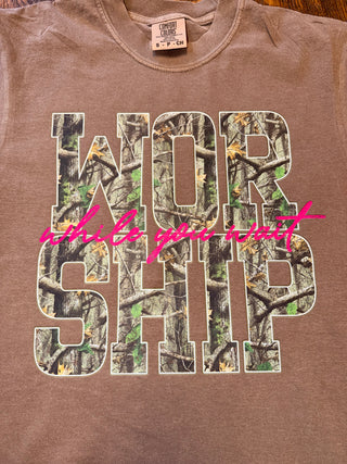 Brown graphic tee with 'Worship While You Wait' text and nature-inspired design.