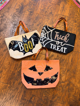 Three Halloween tote bags with sequin designs: a bat with 'Boo!', a pumpkin face, and 'Trick or Treat' with a spider web.