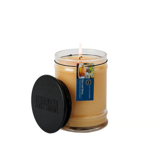 An 8oz glass jar candle with a black wooden lid, featuring a warm, creamy wax and a hangtag.