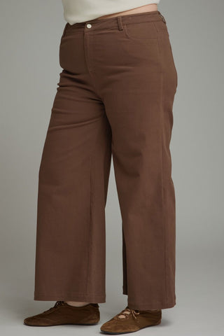 Brown cropped pants with a comfortable cotton blend, shown on a standing model.