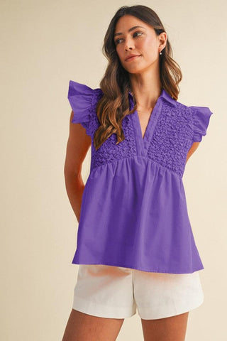 Purple babydoll top with popcorn smocking, ruffle sleeves, and a V-neck collar worn by a model.