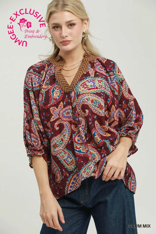 Woman wearing a plum paisley print boho blouse with a V-neckline and balloon sleeves.