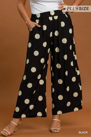 Black wide leg crop pants with large white polka dots, featuring an elastic waistband and side pockets.